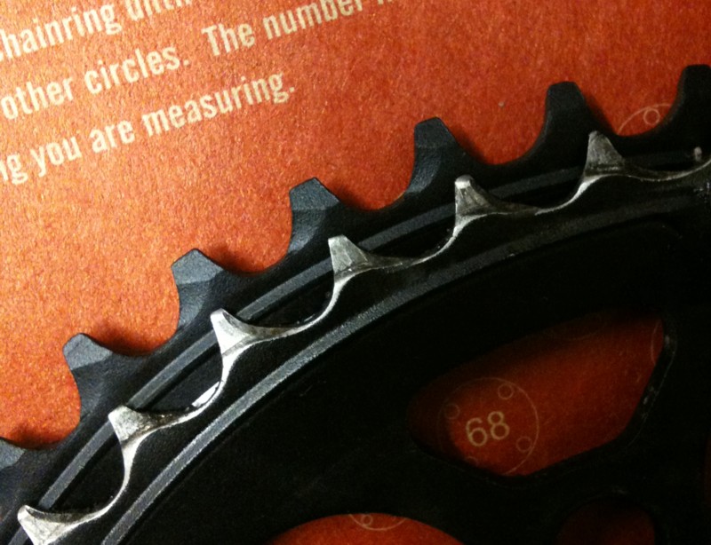 A worn chainring shown alongside a new one. Notice the wide gaps between teeth where material has been worn away.